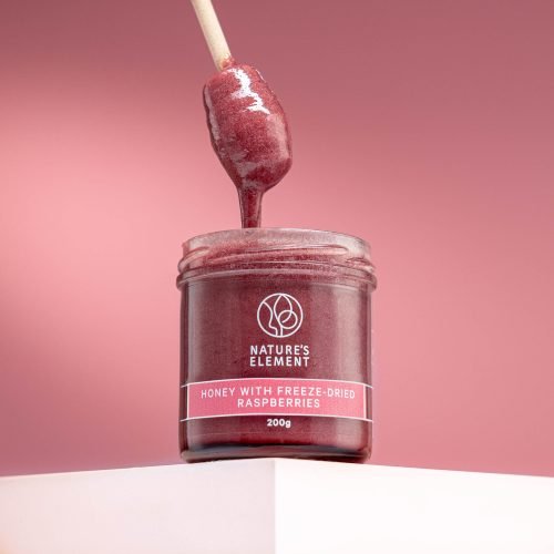 Nature’s Element raspberry honey with wooden dipper – sweet natural fruit blend