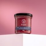 Nature’s Element honey with freeze-dried blackcurrants in glass jar on pink background – natural berry honey